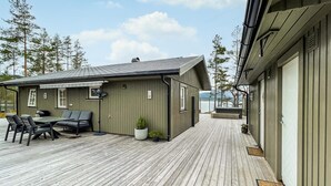 A wooden deck with a dining area and outdoor seating. - Cozy home in Nissedal with house sea view (Nissedal)