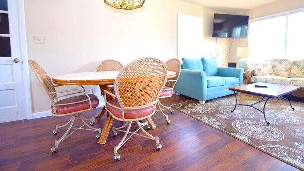 A dining area with a wooden table and wicker chairs, a blue sofa, and a patterned rug. - Bayshore Drive 211 3 Bedroom Home by RedAwning (Ocean City)