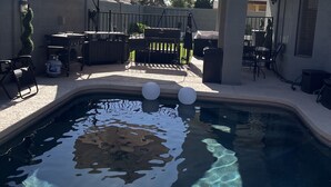 A swimming pool with clear water, surrounded by a patio area with outdoor furniture and a covered seating area. - Remodeled 2 story home w/ pool 8 minutes from the State Farm Stadium! (Glendale)
