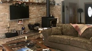 Un saló amb una llar de pedra, un televisor gran fixat a la paret, un sofà i una taula de centre amb llibres.