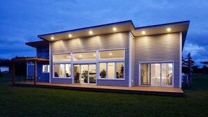 Ein modernes, zweistöckiges Haus mit großen Fenstern und einer überdachten Terrasse.