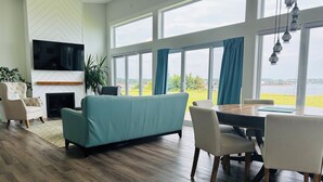 Ein modernes Wohnzimmer mit einer Couch, Sesseln, einem Esstisch und einem Fernseher.
