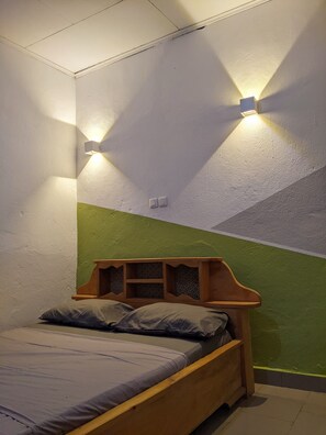 Una camera da letto con un letto di legno, pareti verde e bianche e due luci a parete.