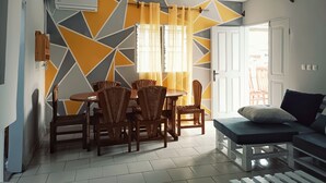 Ein Essbereich mit Tisch und Stühlen, einer Couch und einer Wand mit geometrischen Mustern.