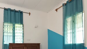 Ein Schlafzimmer mit einem hölzernen Bett, lindgrünen Vorhängen und einer blauen Akzentwand.