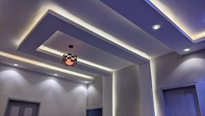 Ein modernes Interieur mit eingelassener Beleuchtung, einer strukturierten Pendelleuchte und einer schlichten Tür.