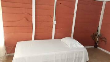 A single bed with white bedding in a room with orange walls and white trim.