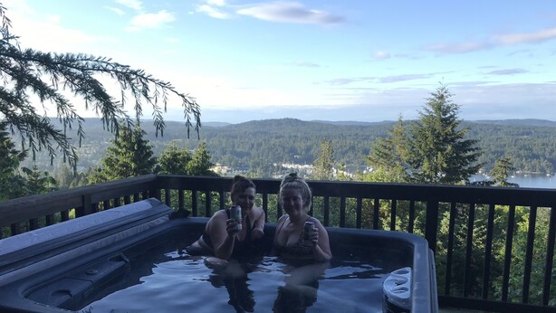 Un jacuzzi en una terraza con vistas a un lago y montañas.