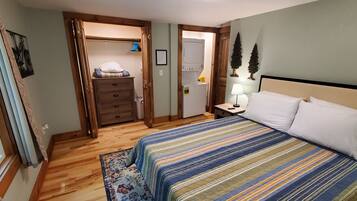 A bedroom with a bed, a nightstand, a dresser, and a walk-in closet.
