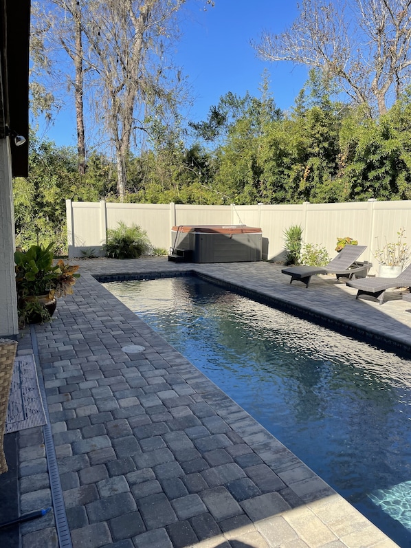 A swimming pool with a hot tub, surrounded by a wooden deck and a white fence. - Close to beach! Family-sized home with pool and hot tub. (Port Orange)