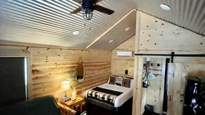 A cozy room with a bed, a green sofa, a ceiling fan, and a small table with a lamp. - Cozy Hill Cabin 2 (Weatherford)