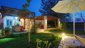 Un espace patio agrémenté d’une pergola, de sièges d’extérieur et d’un panier de basketball.