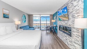 Ett hotellrum med en säng, en sittgrupp med utsikt, en öppen spis och en balkong med utsikt över staden.