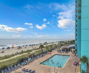 Un complexe hôtelier de bord de mer doté d’une piscine, de parasols et offrant une vue sur l’océan.