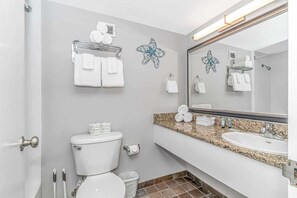 Un baño con inodoro, lavabo, toallero y espejo.