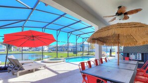 Un espacio al aire libre cubierto con piscina, sillas rojas y una mesa.
