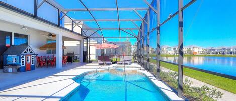Une piscine dotée d’une structure en verre, d’un espace extérieur aménagé et offrant une vue sur un lac.