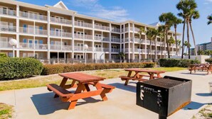 Un hôtel doté de nombreux balcons, de tables de pique-nique extérieures et d’un barbecue.