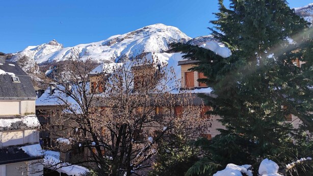 Ein Gebäude mit schneebedecktem Dach und einem Berg im Hintergrund.