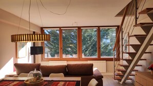 Ein modernes Wohnzimmer mit einer Couch, einem Esstisch und einer Treppe.