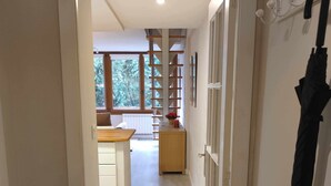 Ein Flur, der zu einer Küche mit einer Holzausstattung und einem Fenster mit Blick auf Bäume führt.