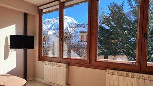 Ein Zimmer mit einem großen Fenster, einem Flachbildfernseher und zwei Heizkörpern.