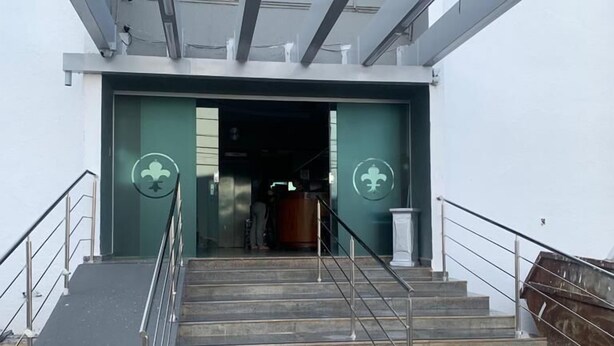 A staircase leading to a building entrance with a green logo on the walls. - Avalon (Goiânia)