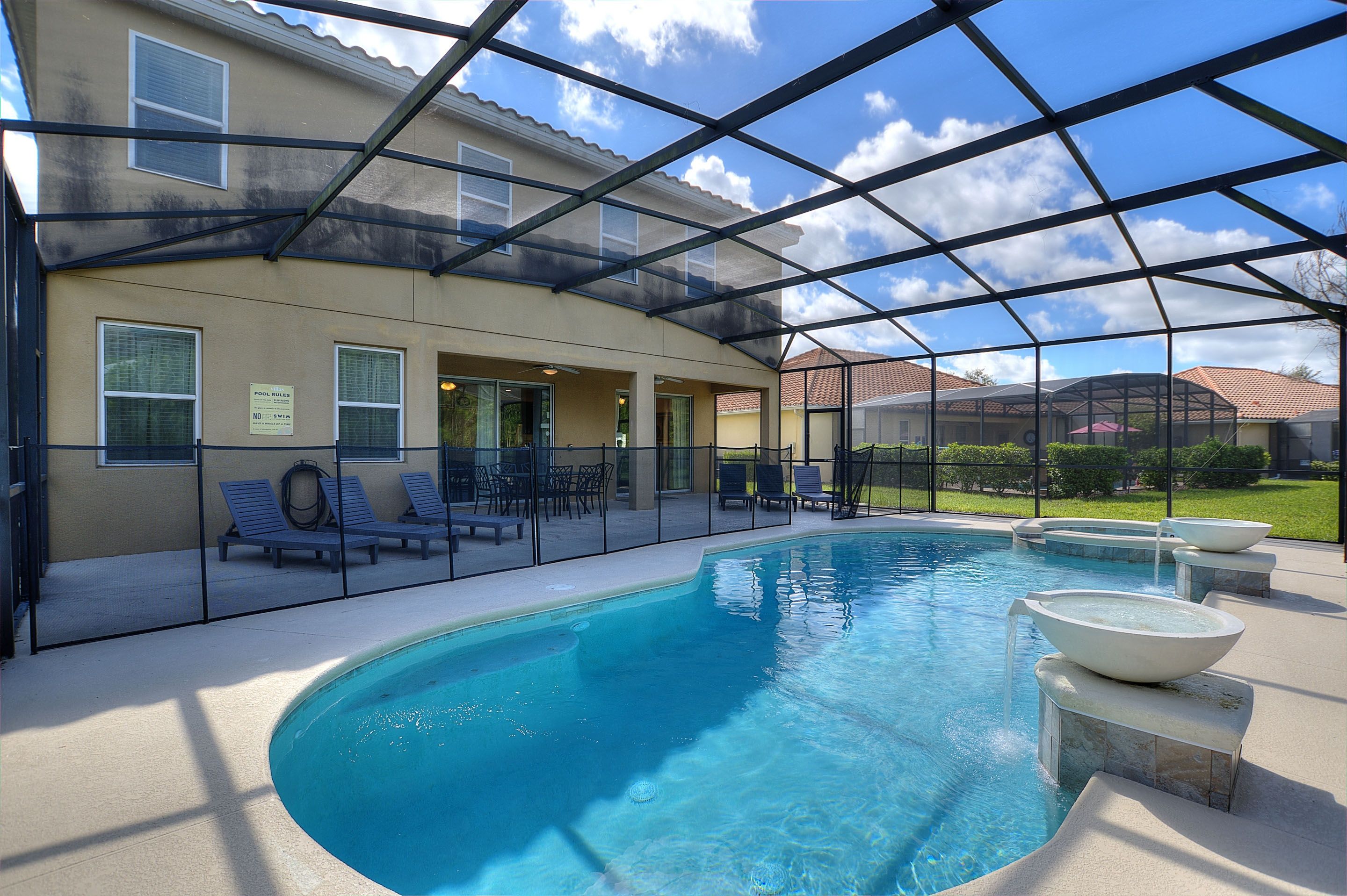A covered swimming pool with lounge chairs and a patio area.