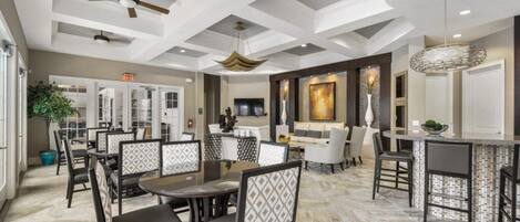 A spacious dining area with high ceilings, ceiling fans, and a modern chandelier.
