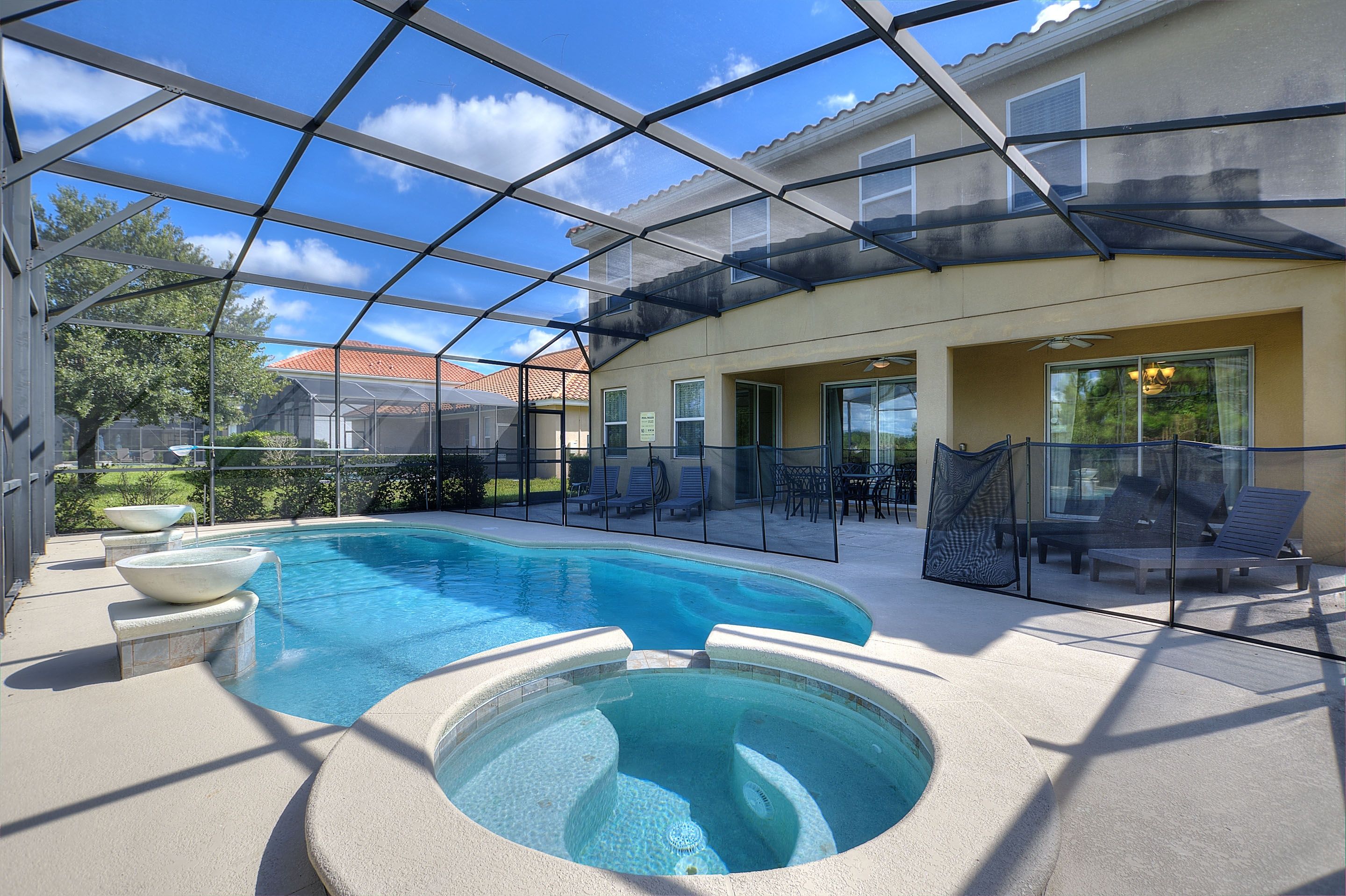 A covered outdoor swimming pool with lounge chairs and a hot tub.