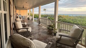 A covered porch with outdoor seating, a ceiling fan, and a view of the ocean. - French Leave South Beach Dogtrot Villa 2 Bedroom Villa (Governor's Harbour)