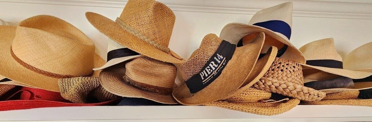 Una colección de sombreros de paja con etiquetas, dispuesta sobre una superficie.