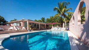 Una piscina con sillas de descanso y un área de estar techada.