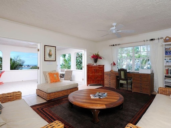 A spacious living room with a round wooden coffee table, a sofa, a red cabinet, and a bookshelf.
