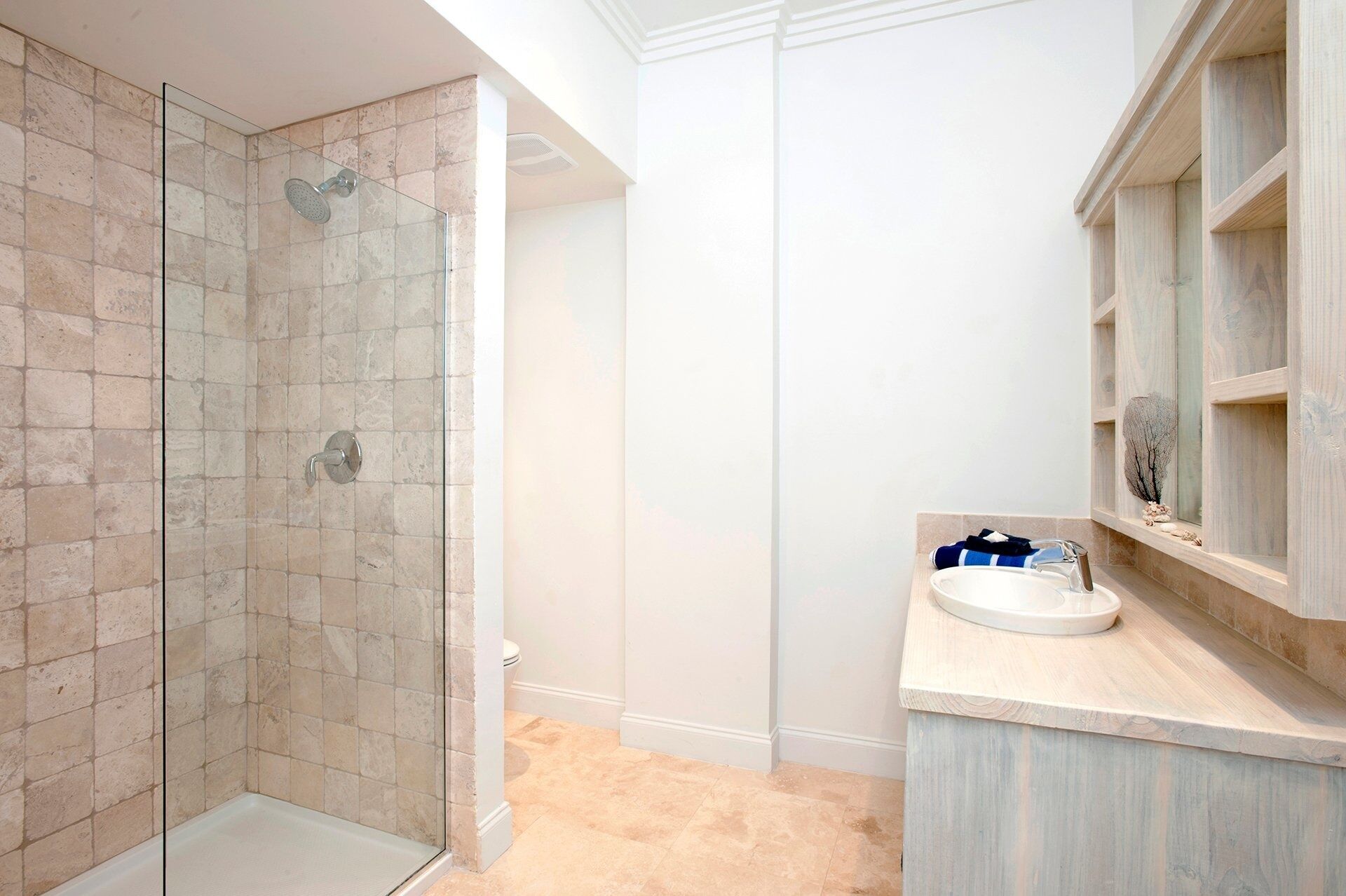 A bathroom with a glass-enclosed shower, a white sink, and a wooden vanity.