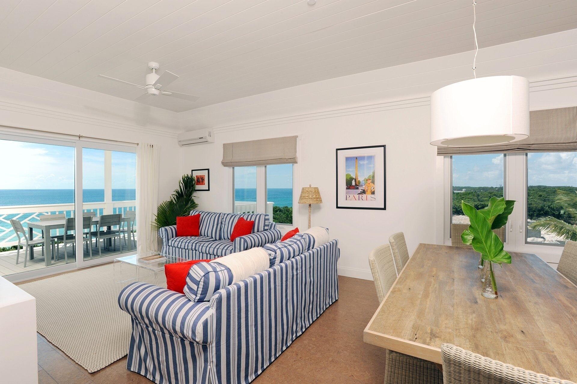 A spacious living area with a large sofa, a dining table, and a view of the ocean.