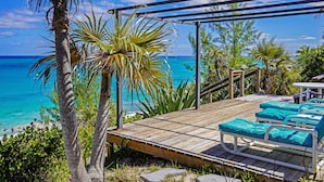 A wooden deck with lounge chairs and a view of the ocean. - Trident Cottage 2 Bedroom Cottage (North Palmetto Point)