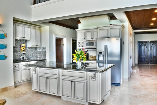 A spacious kitchen with a large island, white cabinetry, and stainless steel appliances.
