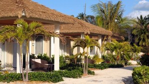 Een resort met rieten villa's, palmbomen en een zandpad.