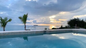 Ein Pool mit Blick auf den Ozean und einen Sonnenuntergang.