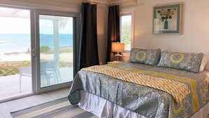 Ein Schlafzimmer mit Bett, Nachttisch, Lampe und Blick auf den Strand.