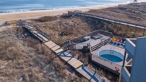 Ein Küstenort mit Holzterrasse, Schwimmbad und Blick auf den Strand.