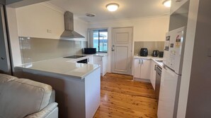 Una cocina compacta con armarios blancos, microondas integrado y refrigerador.