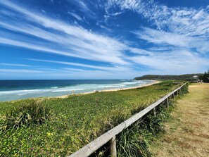 Un paysage côtier avec une clôture en bois, une plage et l’océan.