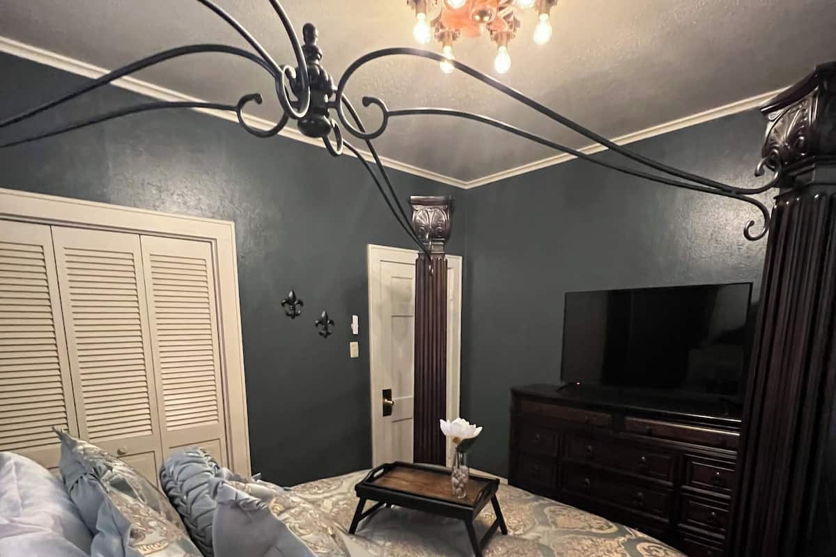 A bedroom with a bed, dresser, TV, and a decorative ceiling light.