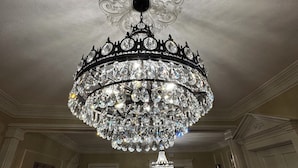 Un imponente candelabro con múltiples niveles de cristal y una ornamentada roseta en el techo.