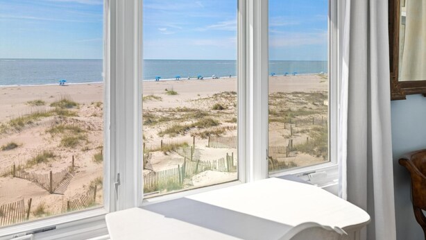 A room with a large window overlooking a beach.