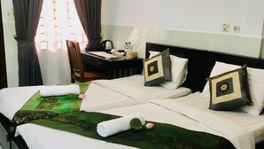 Une chambre d’hôtel avec un lit bien fait, une table de chevet avec une lampe et une fenêtre avec des rideaux.