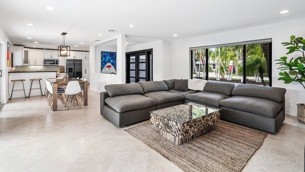 A modern living room with a sectional sofa, a glass coffee table, and a dining area with a wooden table and chairs.