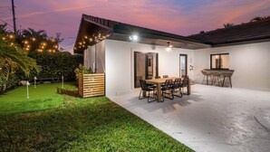 A modern house with a patio, a dining table, and a barbecue area.